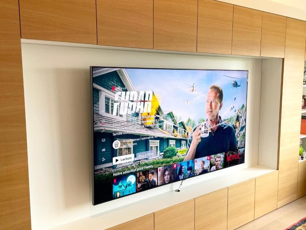 Un televisor de pantalla plana montado en una pared con diseño de panel de madera.