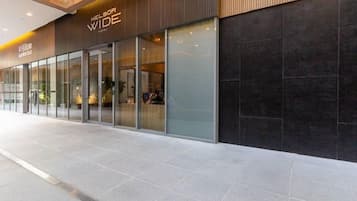 Una entrada de hotel moderna con puertas de vidrio, un cartel que dice 'Hilton Garden Inn' y un piso de baldosas.