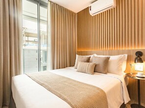 A hotel room with a large bed, a bedside table with a lamp, and a view of the outside. - Helbor Wide (São Paulo)