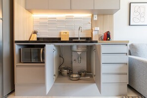 A compact kitchen with a microwave, sink, and storage cabinets. - Helbor Wide (São Paulo)