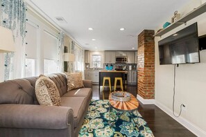 A living room with a sofa, a coffee table, and a kitchen in the background. - Work & Relax in KC: Comfortable 2nd Floor Apt (2BR/2BA)| Near Plaza (Kansas City)