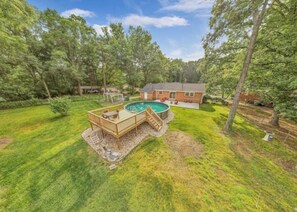 A backyard with a swimming pool, deck, and a house. - 3 King Bedroom House with Pool in Charlott (Charlotte)