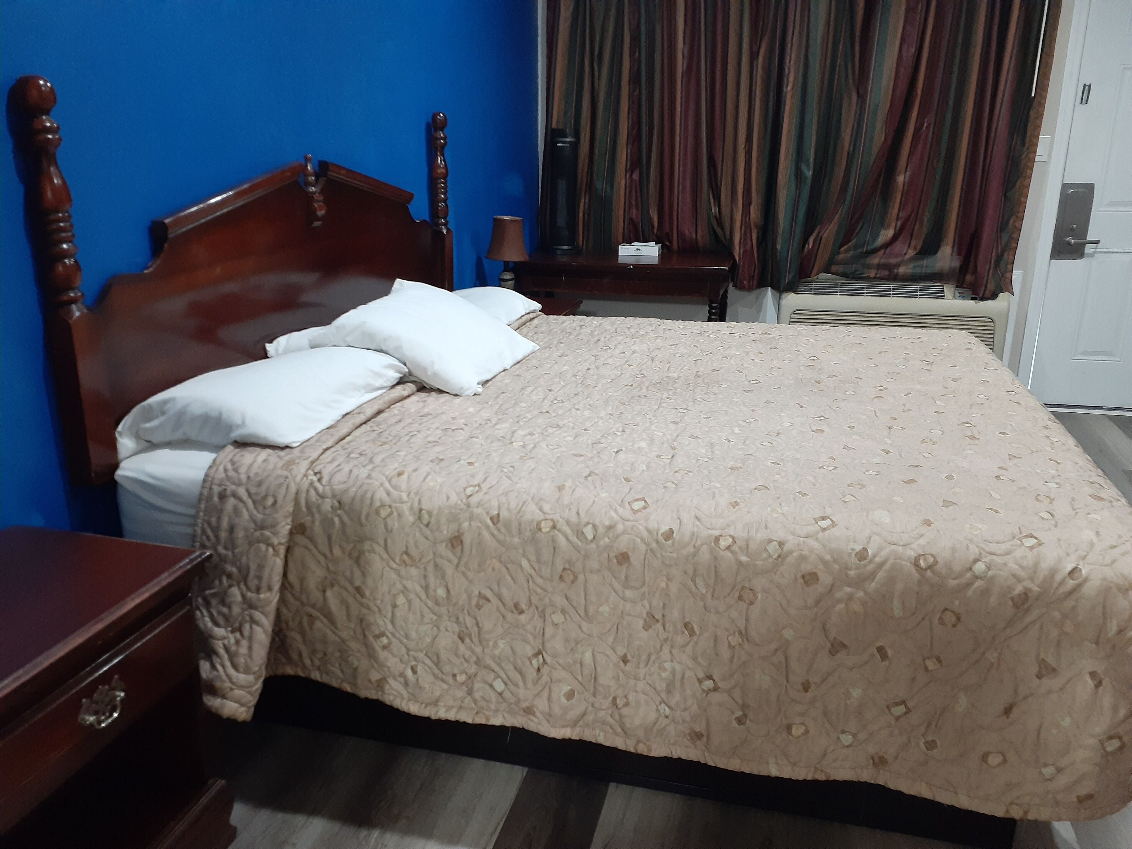 A neatly made bed with a patterned bedspread, a wooden headboard, and white pillows.