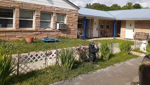 A two-story building with stone exterior walls, a blue roof, and a small front garden with a trampoline and a statue. - Scenic River Inn Wartburg Hwy 27 (Wartburg)