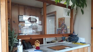A counter with a wooden cabinet, a mirror, a plant, a phone, a small statue, and various papers and a pen. - Scenic River Inn Wartburg Hwy 27 (Wartburg)