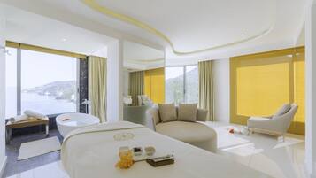 Habitación de hotel moderna con una cama grande, una zona de estar con una silla, una bañera y vistas a la montaña.