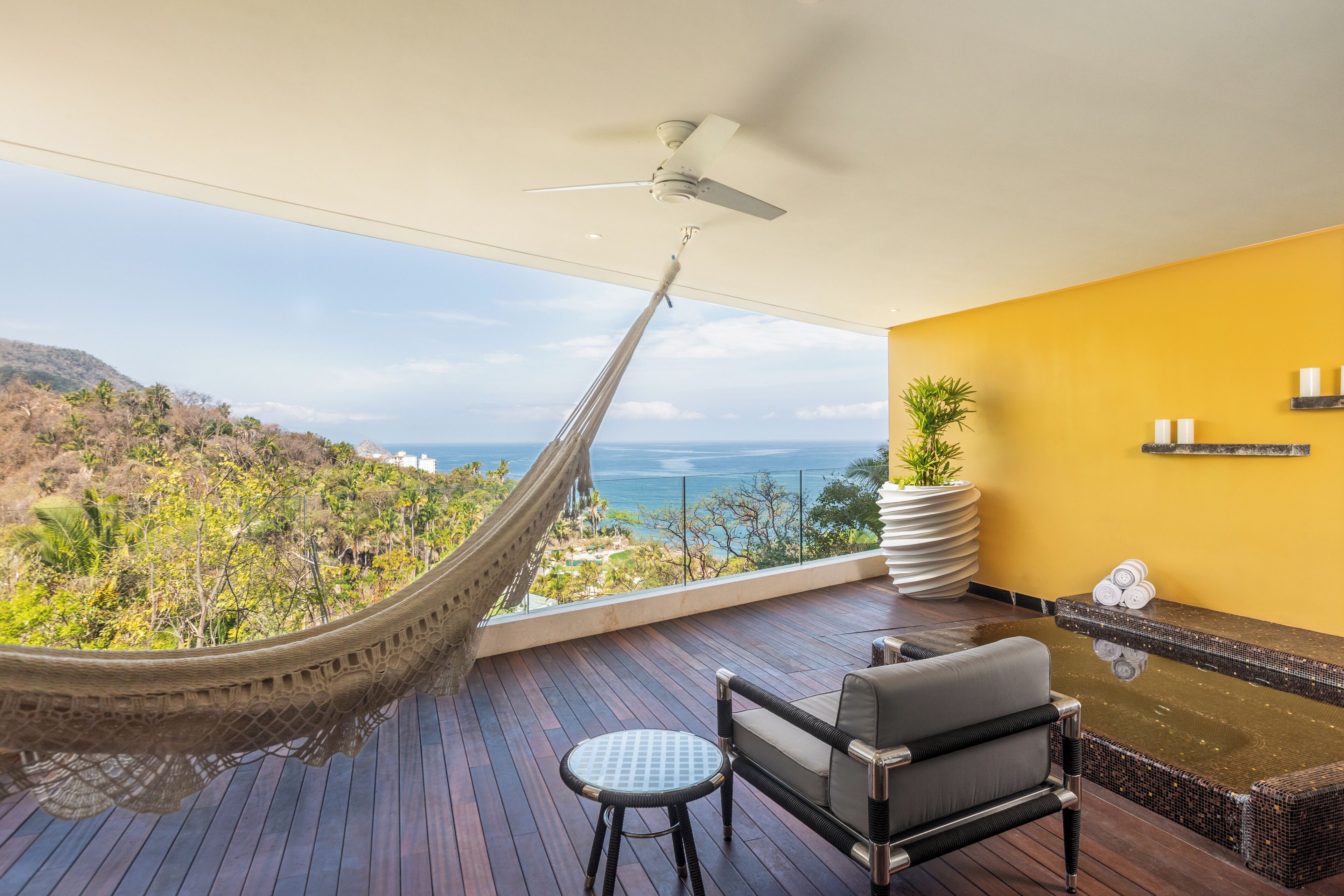 A balcony with a hammock, a seating area, and a view of the ocean.