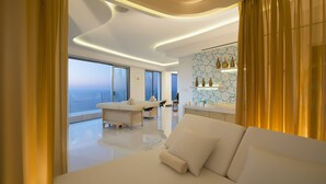 A modern hotel room with a large bed, a sitting area, a vanity with mirrors, and a view of the ocean. - Hotel Mousai Puerto Vallarta - All Inclusive - Adults Only (Puerto Vallarta)