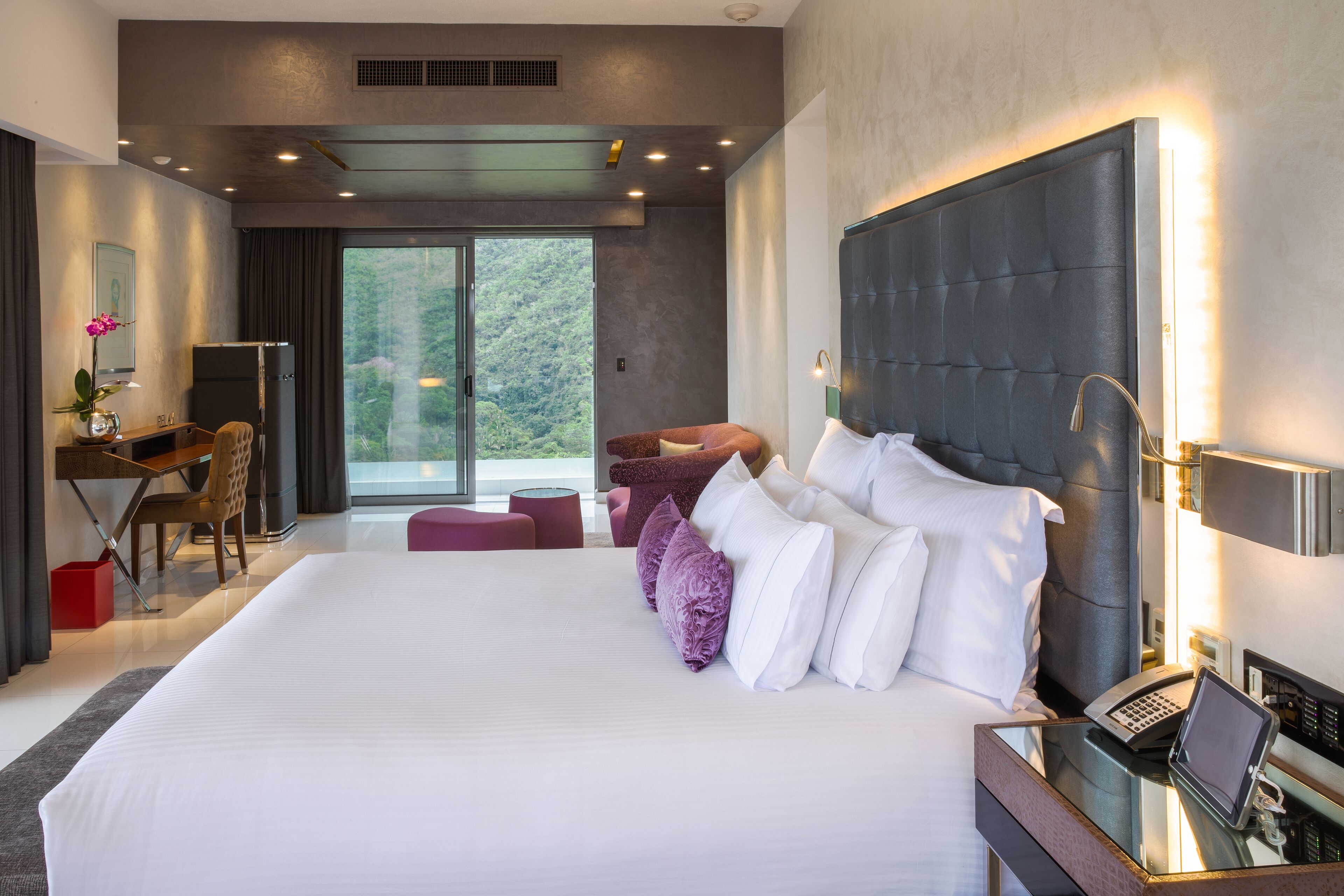 Habitación de hotel moderna con una cama grande, un escritorio y vistas al exterior.