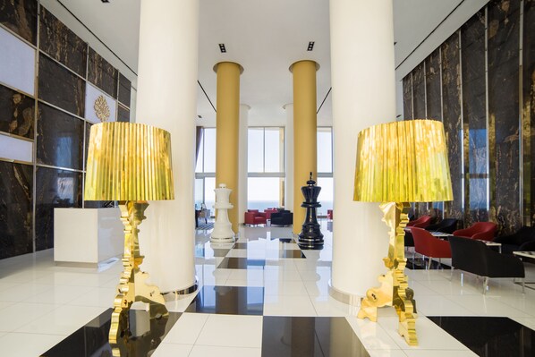 A lobby with a checkered floor, large columns, and two golden lamps. - Hotel Mousai Puerto Vallarta - All Inclusive - Adults Only (Puerto Vallarta)