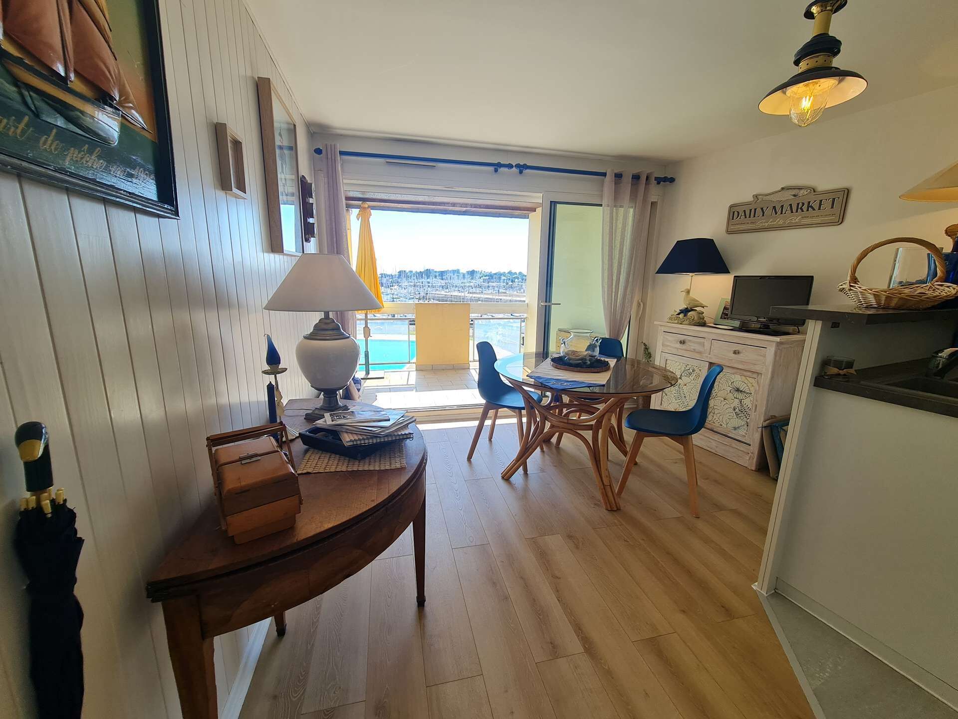 A cozy room with a wooden table, chairs, a lamp, and a view of the sea.