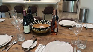 A modern kitchen with a wooden dining table set for a meal, featuring a central decorative bowl, wine bottles, and a stainless steel refrigerator. - Spectacular Mountain Retreat (Winter Park)