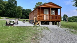 Une cabane en bois avec une véranda, deux chaises et une table.