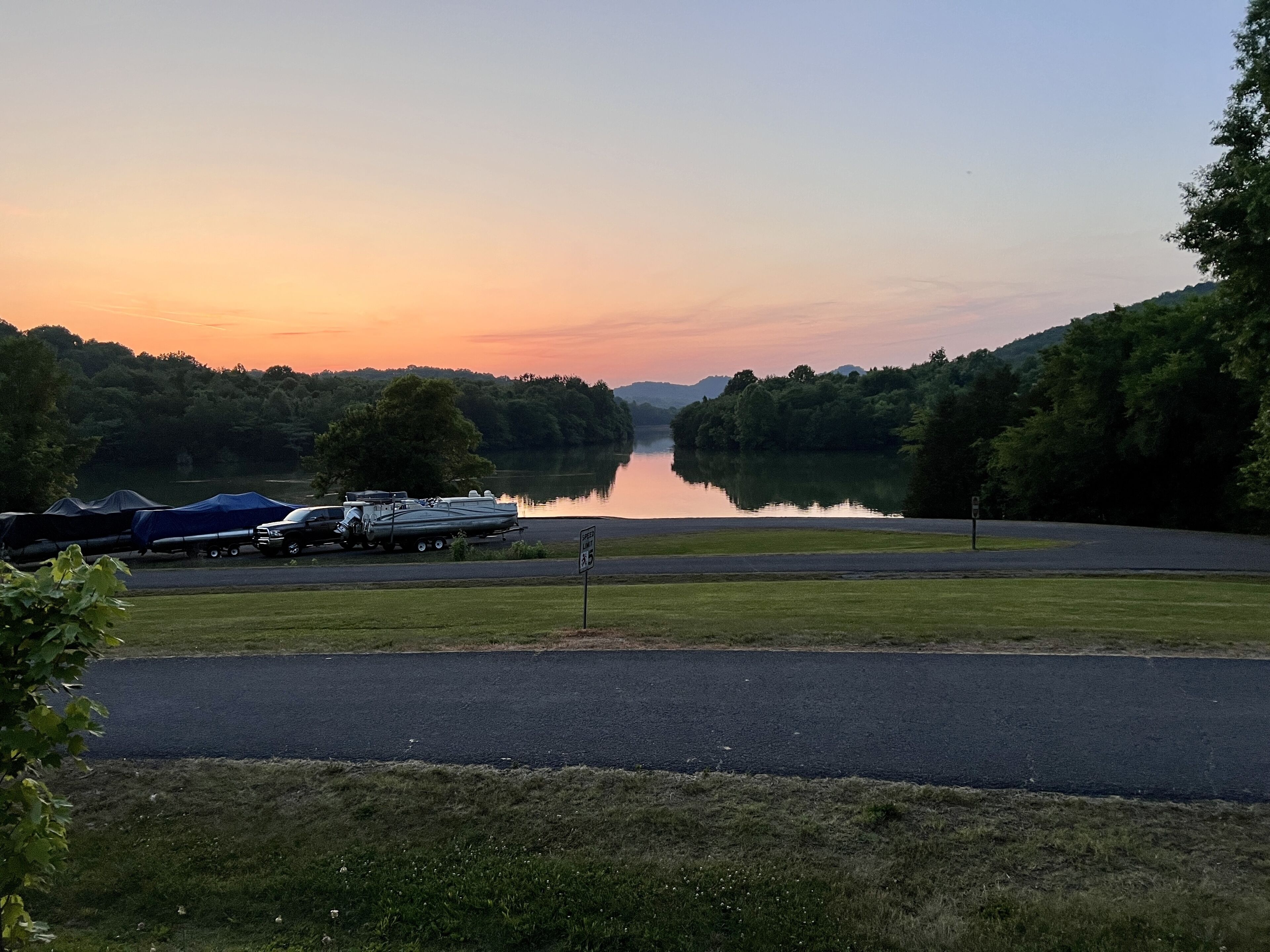 A lakeside view with boats docked, a road, and a grassy area.