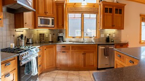 Una cocina con armarios de madera, una estufa de acero inoxidable, un microondas y un lavavajillas.