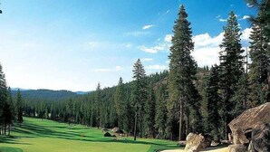 Campo de golf con búnkeres de arena, árboles y cielo despejado.