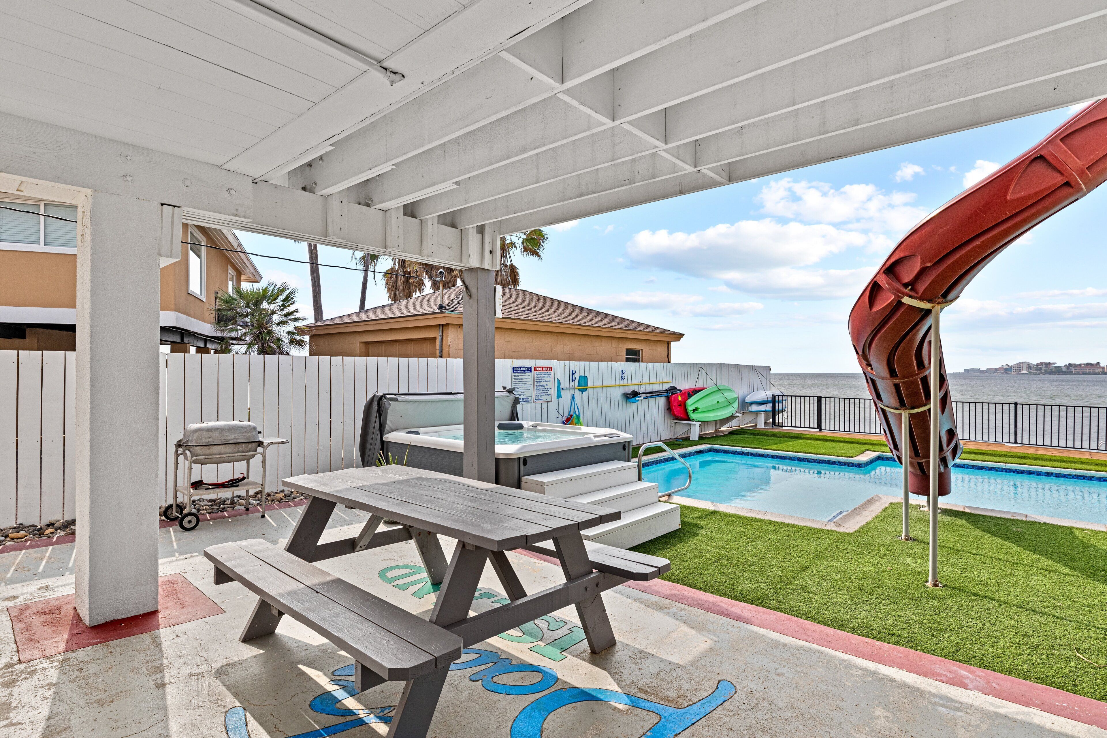 Un patio cubierto con piscina, jacuzzi y una parrilla.