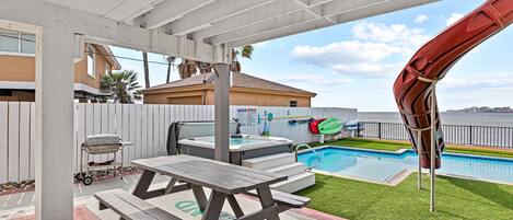Un patio cubierto con piscina, jacuzzi y una parrilla.