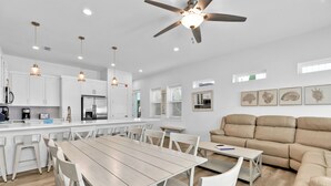 A modern kitchen with white cabinets, a stainless steel refrigerator, and pendant lighting.