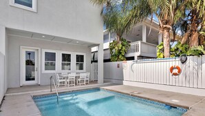 A swimming pool with a tiled edge, a white fence, and a lifebuoy attached to the fence.
