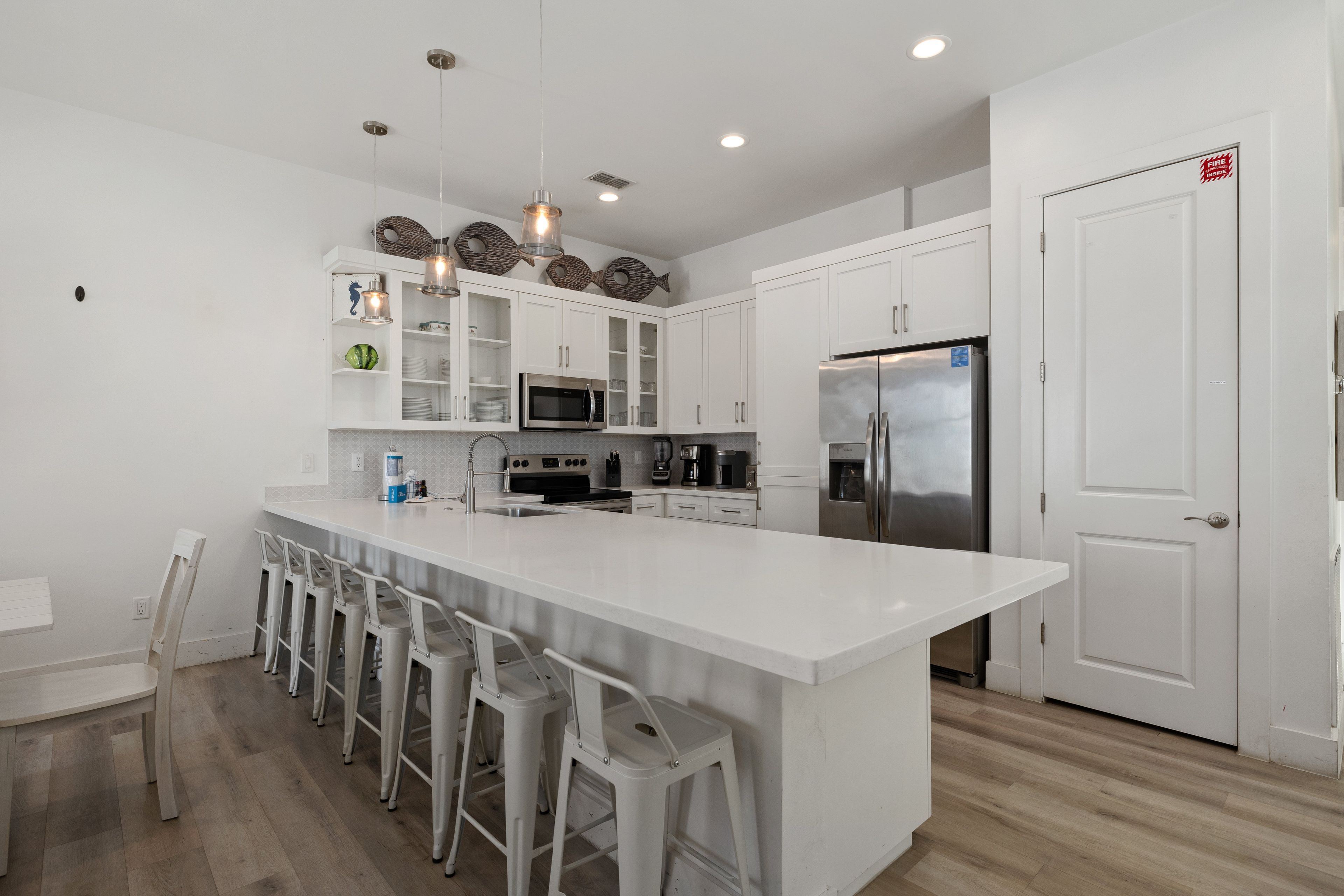 A modern kitchen with white cabinetry, stainless steel appliances, and a central island with bar stools.