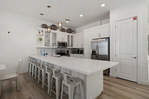 A modern kitchen with white cabinetry, stainless steel appliances, and a central island with bar stools.
