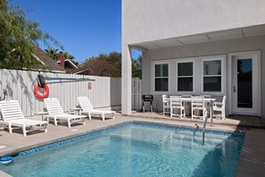 Une piscine avec des chaises longues et un barbecue.