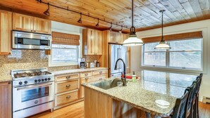 A kitchen with wooden cabinets, stainless steel appliances, a granite countertop, and a window with a view. - Stowe Sticks: 4 br, a/c, gas fireplace, firepit, deck! (Stowe)