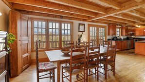 Un comedor de madera con una gran mesa y sillas, una cocina con armarios de madera y ventanas amplias que dan al exterior.