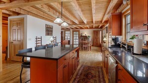 Una cocina amplia con vigas de madera, una isla grande y un comedor con sillas y una mesa.