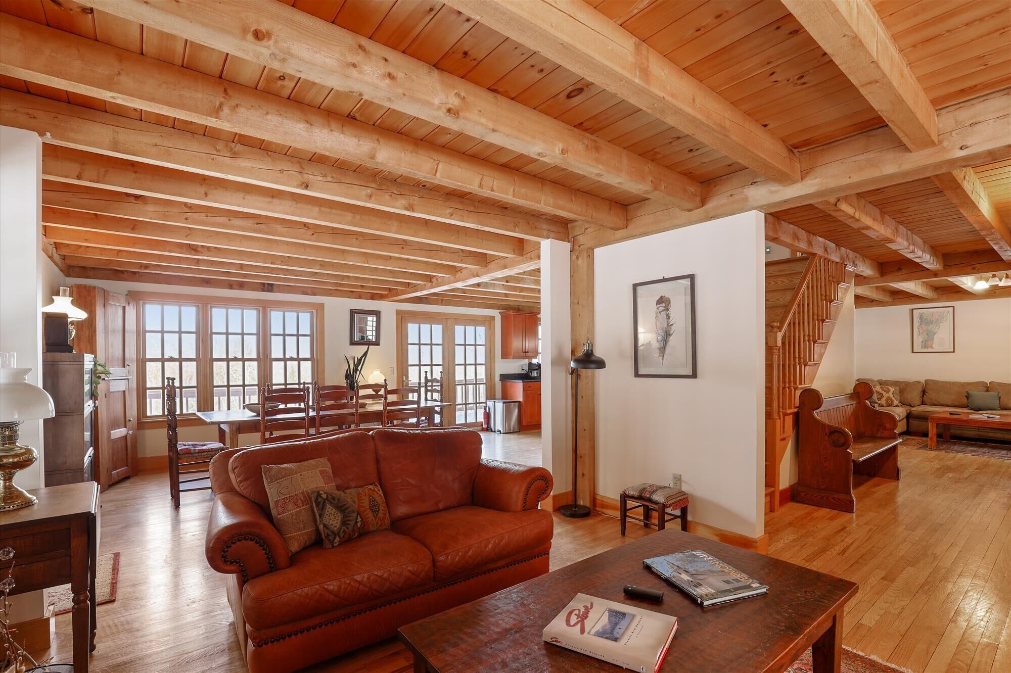 Ein geräumiges Wohnzimmer mit Holzboden, einem Ledersofa, einem Couchtisch und einem Essbereich mit Holzsesseln und einem Tisch.