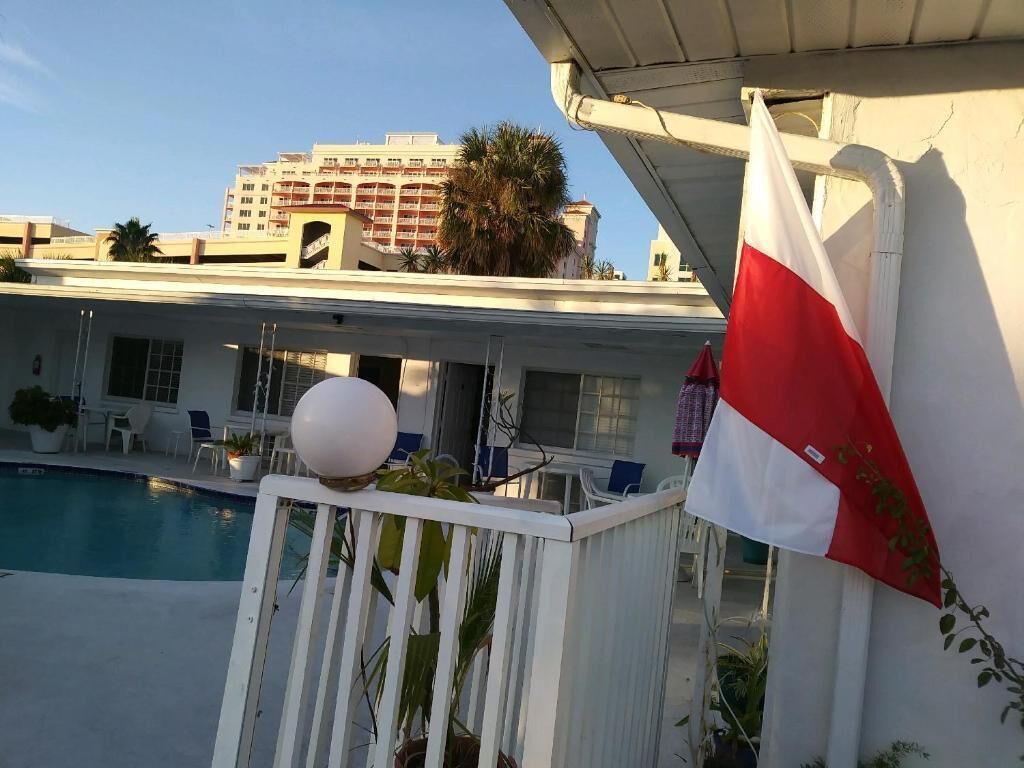 Ein Poolbereich mit einer Flagge, einem weißen Zaun und einem Gebäude im Hintergrund.