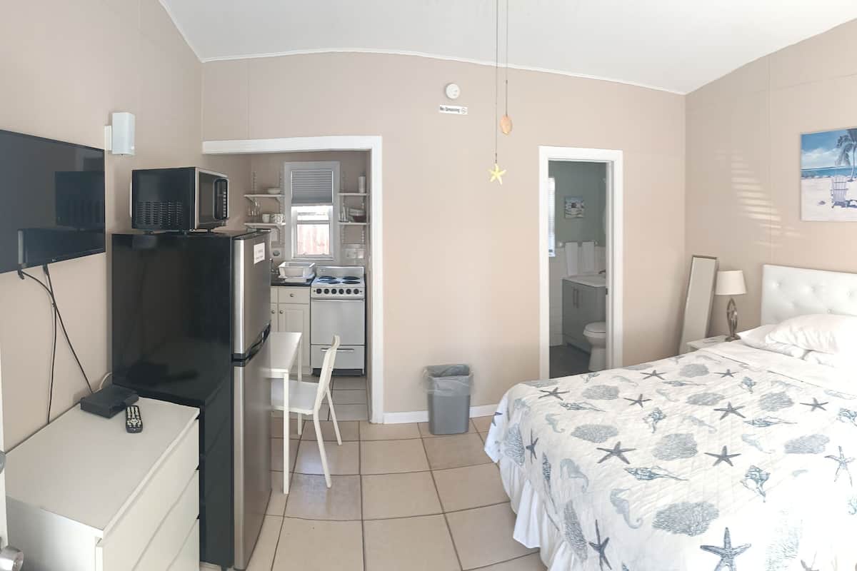 A hotel room with a bed, a desk with a computer, a TV, and a microwave.