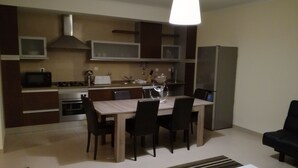 A modern kitchen with a dining area, a refrigerator, and a TV. - T2 Novo Alto do Quintão (Portimão)