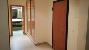 A hallway with a wooden door, a mirror, and a sink in the background. - T2 Novo Alto do Quintão (Portimão)
