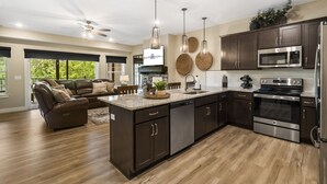 Una cocina moderna con armarios oscuros, electrodomésticos de acero inoxidable y una isla central.