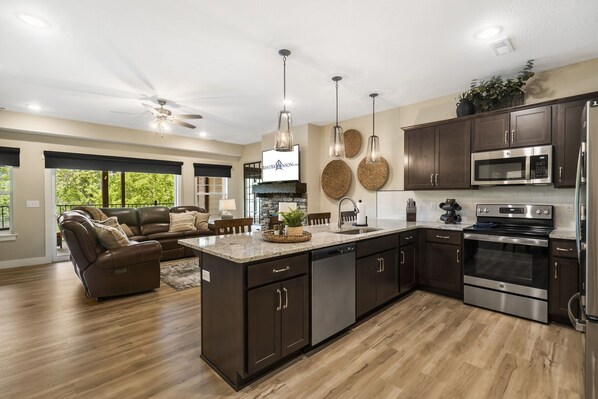 A modern kitchen with dark cabinets, stainless steel appliances, and a central island. - Lakefront on Taneycomo with Fireplace, Just Minutes from Branson Landing (Branson)