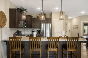 Une cuisine avec des meubles en bois foncé, des appareils électroménagers en acier inoxydable et un îlot central doté de tabourets de bar.