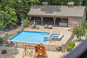A swimming pool with a hot tub, a covered patio with seating, and a wooden play structure. - Lakefront on Taneycomo with Fireplace, Just Minutes from Branson Landing (Branson)
