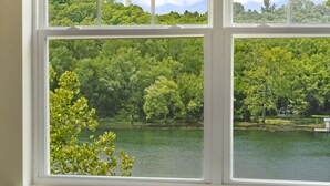 Una ventana con vista a un lago rodeado de árboles verdes y frondosos.