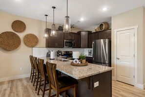 A modern kitchen with dark wooden cabinets, stainless steel appliances, and a granite countertop. - Lakefront on Taneycomo with Fireplace, Just Minutes from Branson Landing (Branson)