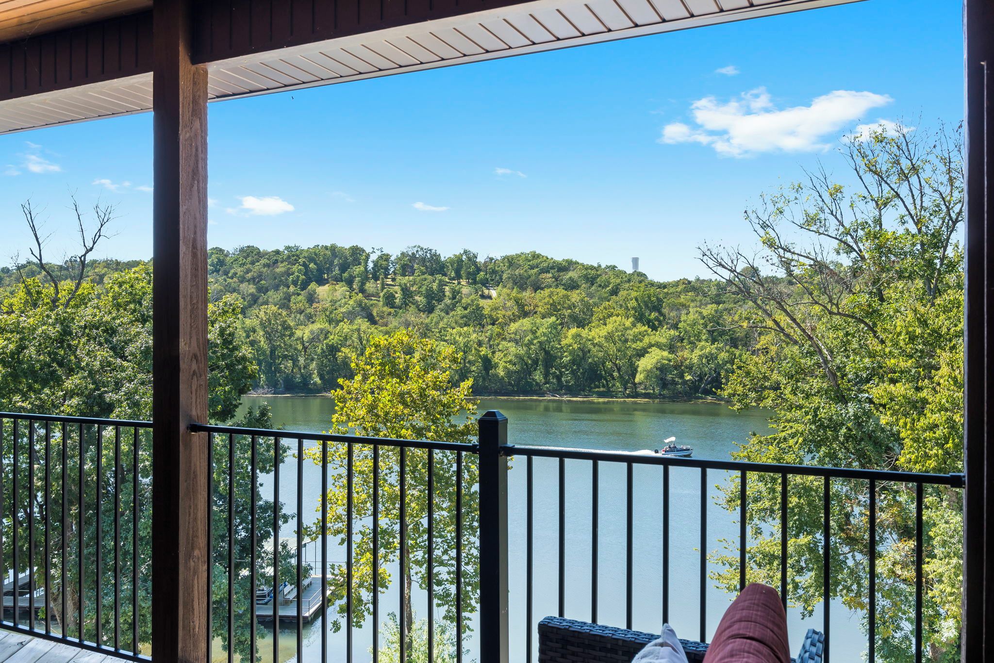 A deck with a view of a lake, surrounded by trees and hills.
