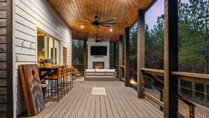 A wooden deck with a fireplace, seating area, and a TV mounted on the wall. - Play-Set, Darts, Large Back Deck, Hot Tub, Pets, Hidden Jewel (Broken Bow)