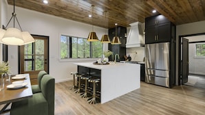 A modern kitchen with a central island, bar stools, stainless steel appliances, and a wooden ceiling. - Play-Set, Darts, Large Back Deck, Hot Tub, Pets, Hidden Jewel (Broken Bow)