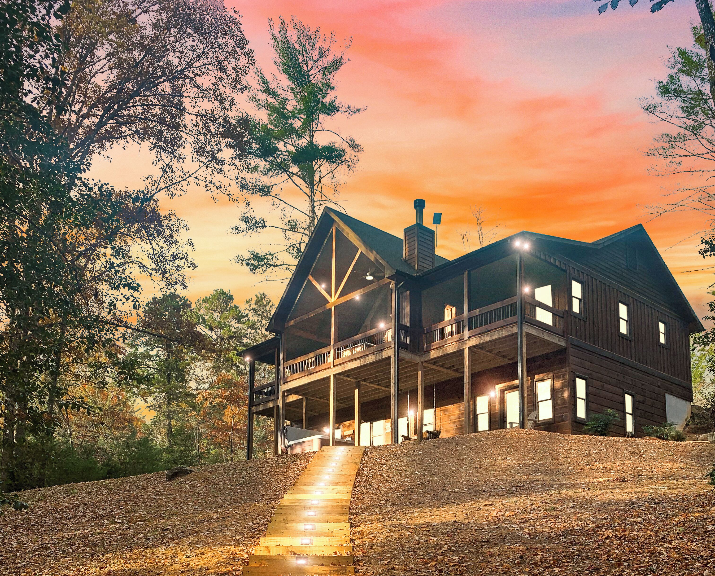 A two-story wooden house with a covered porch and a staircase leading up to it.