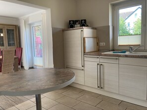A compact kitchen with a built-in refrigerator, a sink, and a window providing natural light.