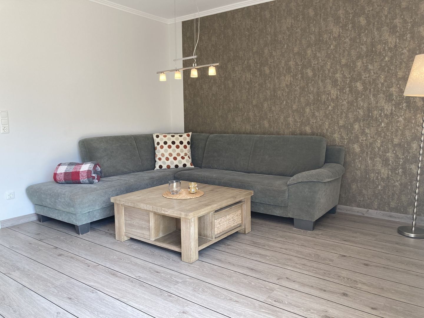Ein modernes Wohnzimmer mit einem grauen Sofa, einem Holztisch und einem Kissen mit Muster.