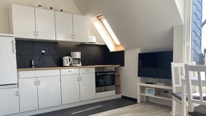 A modern kitchen with white cabinets, a built-in oven, and a coffee maker.