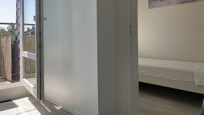 A bedroom with a bed, a window, and a painting on the wall.