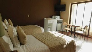 A hotel room with a bed, a desk with a TV, and a chair.